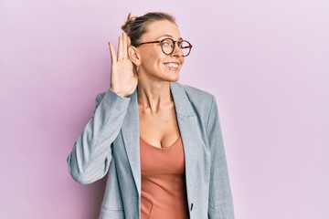 Poster - Beautiful caucasian woman wearing business jacket and glasses smiling with hand over ear listening an hearing to rumor or gossip. deafness concept.