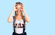 © Krakenimages.com - Beautiful caucasian woman with blonde hair wearing octoberfest traditional clothes doing ok gesture like binoculars sticking tongue out, eyes looking through fingers. crazy expression.