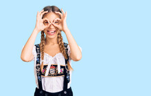 Beautiful Caucasian Woman With Blonde Hair Wearing Octoberfest Traditional Clothes Doing Ok Gesture Like Binoculars Sticking Tongue Out, Eyes Looking Through Fingers. Crazy Expression.