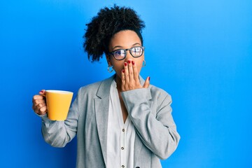 Wall Mural - Young african american girl wearing business clothes drinking a cup of coffee covering mouth with hand, shocked and afraid for mistake. surprised expression