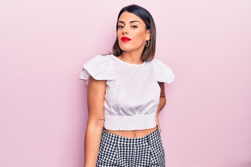 Wall Mural - Young beautiful brunette woman wearing casual clothes standing over isolated pink background