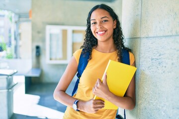 Poster - Young african american student smiling happy and holding book at university.