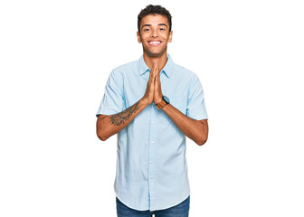 Young handsome african american man wearing casual clothes praying with hands together asking for forgiveness smiling confident.