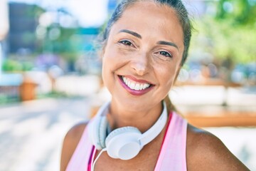 Wall Mural - Middle age sportswoman smiling happy  wearing headphones at the park