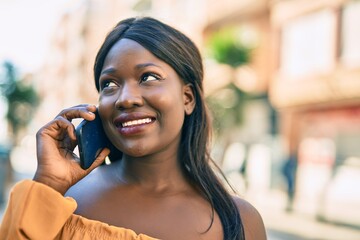 Young african american woman smiling happy talking on the smartphone at the city.