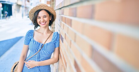 Young beautiful girl smiling happy leaning on the wall at street of city