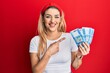 © Krakenimages.com - Young caucasian woman holding 1000 hungarian forint banknotes smiling happy pointing with hand and finger