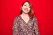 © Krakenimages.com - Young beautiful redhead woman wearing floral casual dress standing over red background with a happy and cool smile on face. Lucky person.