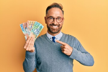 Poster - Handsome middle age man holding australian dollars smiling happy pointing with hand and finger