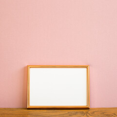 Wall Mural - Empty picture frame on wooden table. pink background