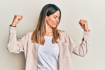 Brunette young woman wearing casual clothes showing arms muscles smiling proud. fitness concept.