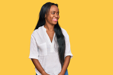 Young black woman wearing casual clothes looking away to side with smile on face, natural expression. laughing confident.