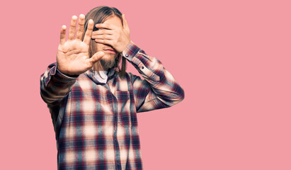 Sticker - Handsome caucasian man with long hair wearing hipster shirt covering eyes with hands and doing stop gesture with sad and fear expression. embarrassed and negative concept.