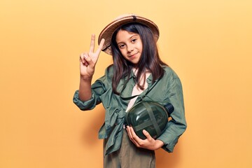 Sticker - Beautiful child girl wearing explorer hat showing and pointing up with fingers number two while smiling confident and happy.