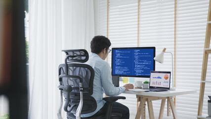 Back rear view of young asian man, freelance data scientist work remotely at home coding programing on Big data mining, AI data engineering, IT Technician Works on Artificial Intelligence Project.