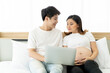 © DG PhotoStock - Happy Asian husband and wife living together in bedroom and browsing the internet for online shopping