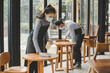 © Vittaya_25 - asian waitress staff wearing protection face mask in apron cleaning table with disinfectant spray for protect infection coronavirus (covid-19) in cafe coffee shop restaurant. new normal concept