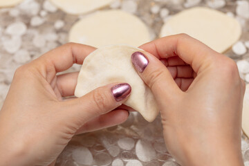 The girl sculpts dumplings from dough.