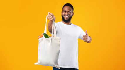 Wall Mural - African Man Holding Eco Bag Gesturing Like, Yellow Background