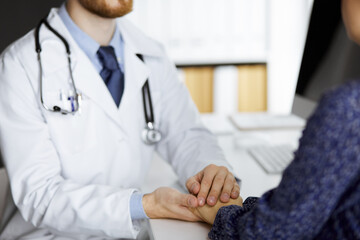 Friendly red-beard doctor reassuring his female patient, close-up. Medical ethics and trust concept, medicine theme