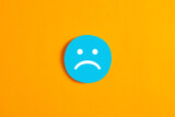 Fototapeta  - Blue round circle with a sad face icon against yellow background.
