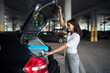 © Nomad_Soul - Young woman puts suitcases into the car on parking
