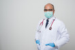 © Chanakon - Asian bald Doctor in white coat, stethoscope, blue glove wearing face mask.put his hand in pocket standing beside camera isolated on white background.