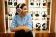 © Nomad_Soul - Young woman listening to music, headphones store