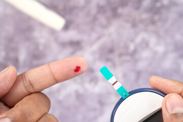 young man's hand measure glucose level at home 