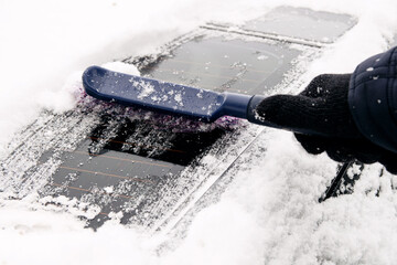 Wall Mural - Gloved male driver sweeps snow off car rear window with special brush