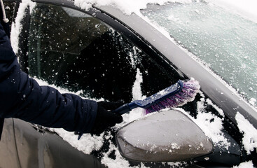 Wall Mural - Male driver sweeps snow off car side window with special brush