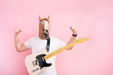 Man With Horse Mask Showing The Strength Of His Arms And With Hanging Electric Guitar