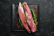Meat. Raw pork tenderloin with spices on a black stone background. Top view. Rustic style.