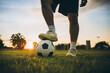 Action sport outdoors of a group of kids having fun playing soccer football for exercise in community rural area under the twilight sunset.