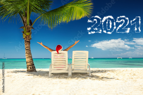 Tela 2021 new year concept with woman in santa's hat  relaxing on tropical beach