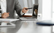 © Iryna - Unknown business people using laptop computer at the desk in modern office. Businessman or male entrepreneur is working with his colleague. Teamwork and partnership concept