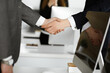 © Iryna - Unknown businessman shaking hands with his colleague or partner while standing straight in modern office, close-up. Business people group at meeting
