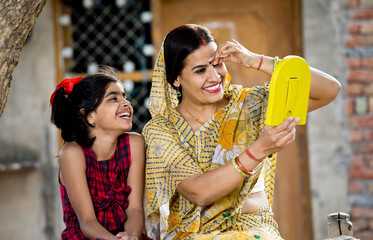 Wall Mural - Joyful girl with mother having fun looking into handheld mirror