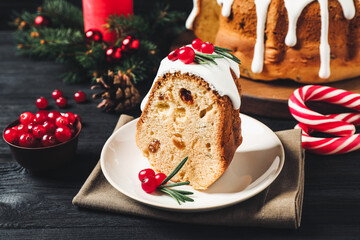 Composition with piece of traditional homemade Christmas cake on black wooden table, closeup