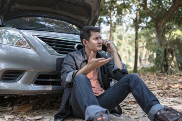 Poster - Man usea cellphone call garage in front of the open hood of a broken car on the road in the forest. Car breakdown concept.