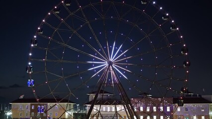 Wall Mural - Ferris wheel with glowing multicolored lights against the night sky.