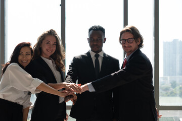 multiethnic business team including man, woman, caucasian and african american people standing together near window and touch hands. international corporate and diversity concept