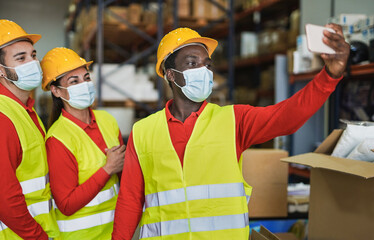 Multiracial people taking a selfie at work in warehouse while wearing surgical face masks for coronvirus