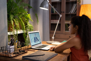 Wall Mural - Diligent schoolgirl listening to explanations of teacher during online lesson