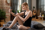 Fototapeta Przestrzenne - Happy young blond woman in black leotard making selfie or recording new video