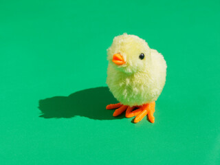 Toy yellow chicken on green background.