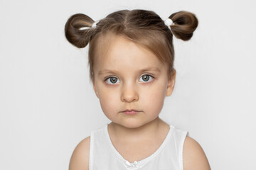 Kids, girls, studio portrait. Close up of face of cute charming little 3 years old girl with blonde hair in ponytails, wearing white tank top, posing to camera on isolated white background