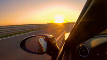 CLOSE UP Summer Evening Sun Rays Shine On A Sportscar Driving Down Empty Freeway