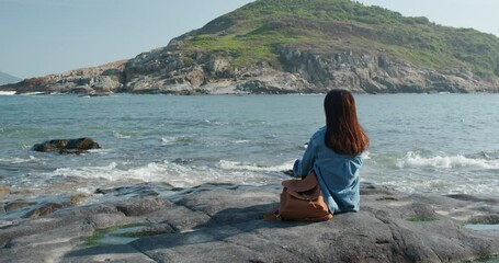 Wall Mural - Woman sit on the rock and enjoy the sea view