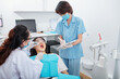 © DragonImages - Dentist checking teeth of young female patient when assistant taking notes in document